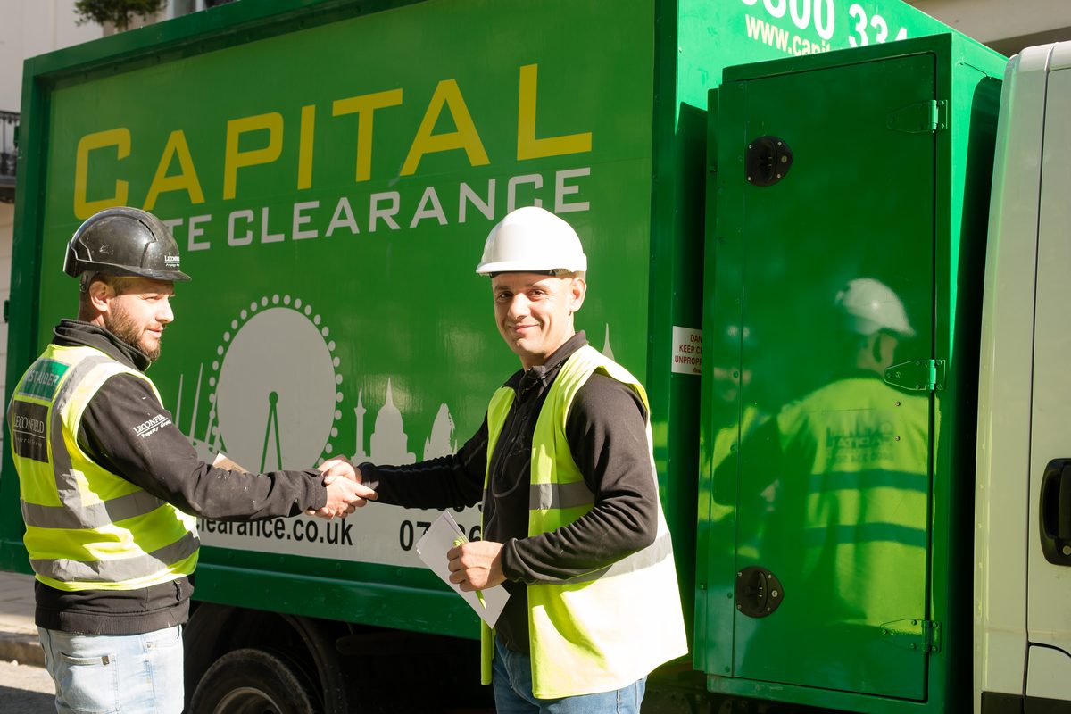 Capital Waste Clearance team shaking hands with a client beside the branded truck